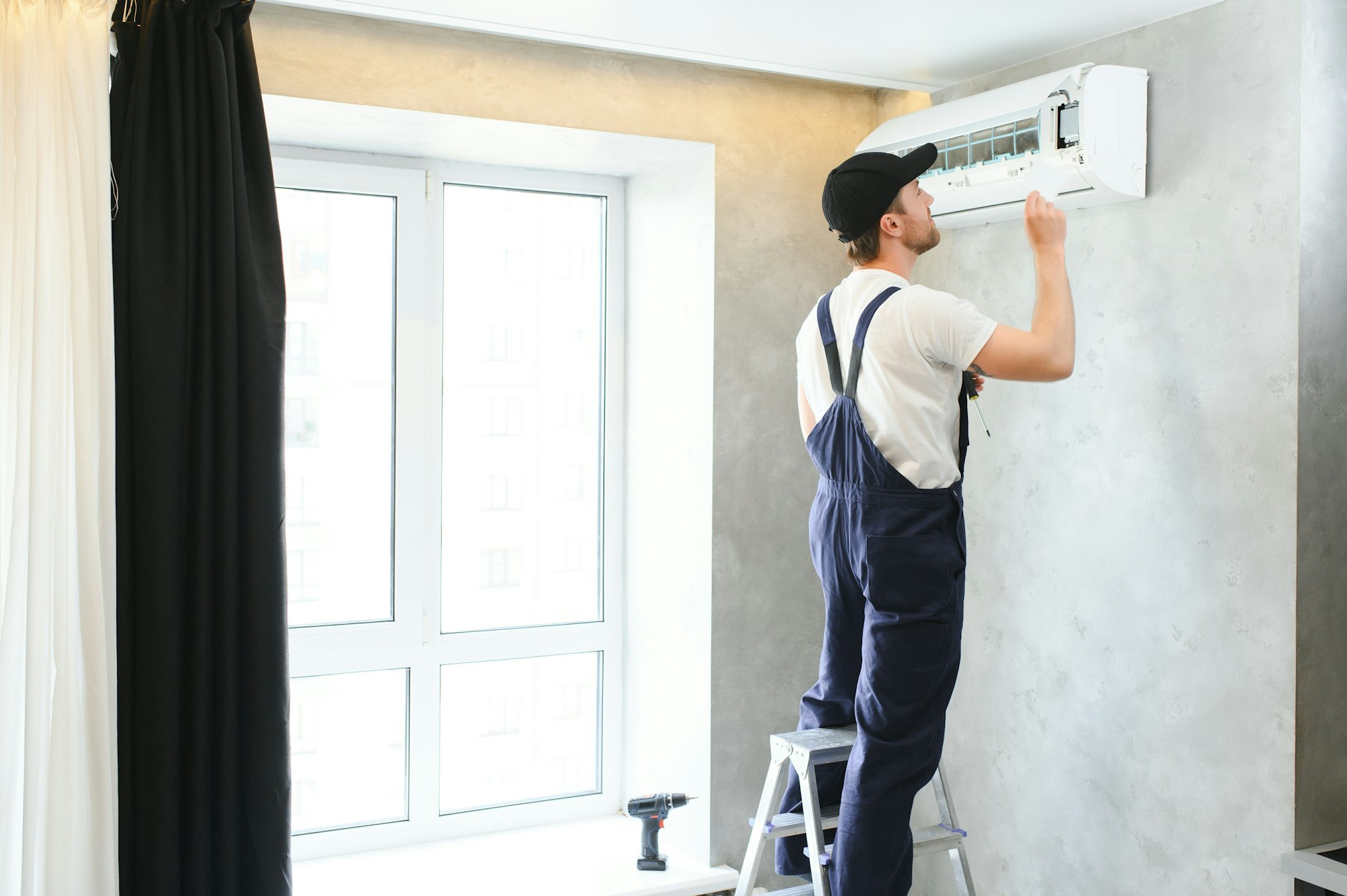 Happy Male Technician Repairing Air Conditioner.