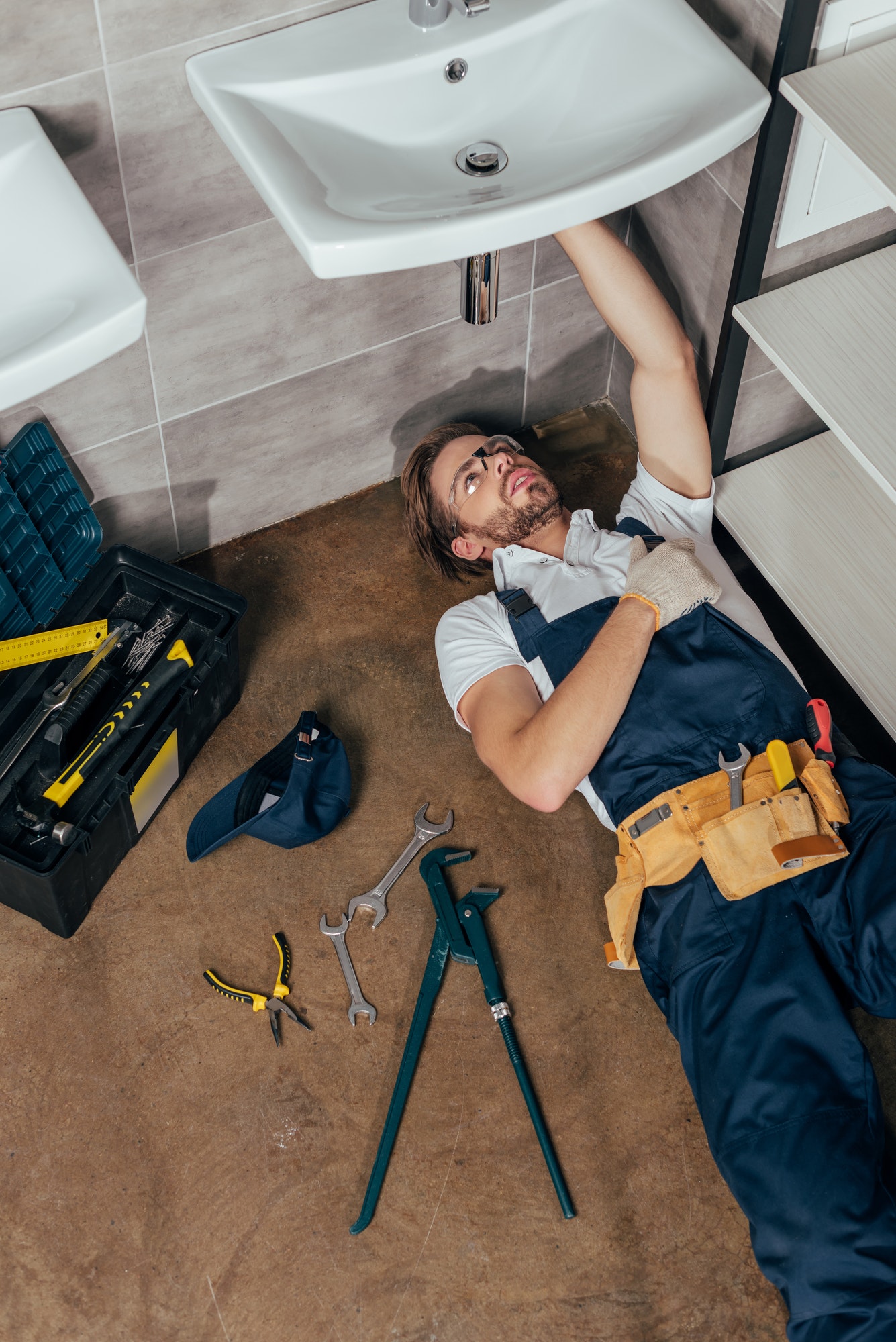 high-angle-view-of-young-male-plumber-fixing-sink-in-bathroom.jpg